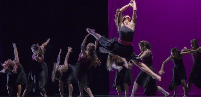 modern dance performance with lead dancer in full leap